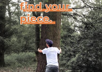 A man hugging a tree with the text “hug a tree, find your piece” above written in orange.